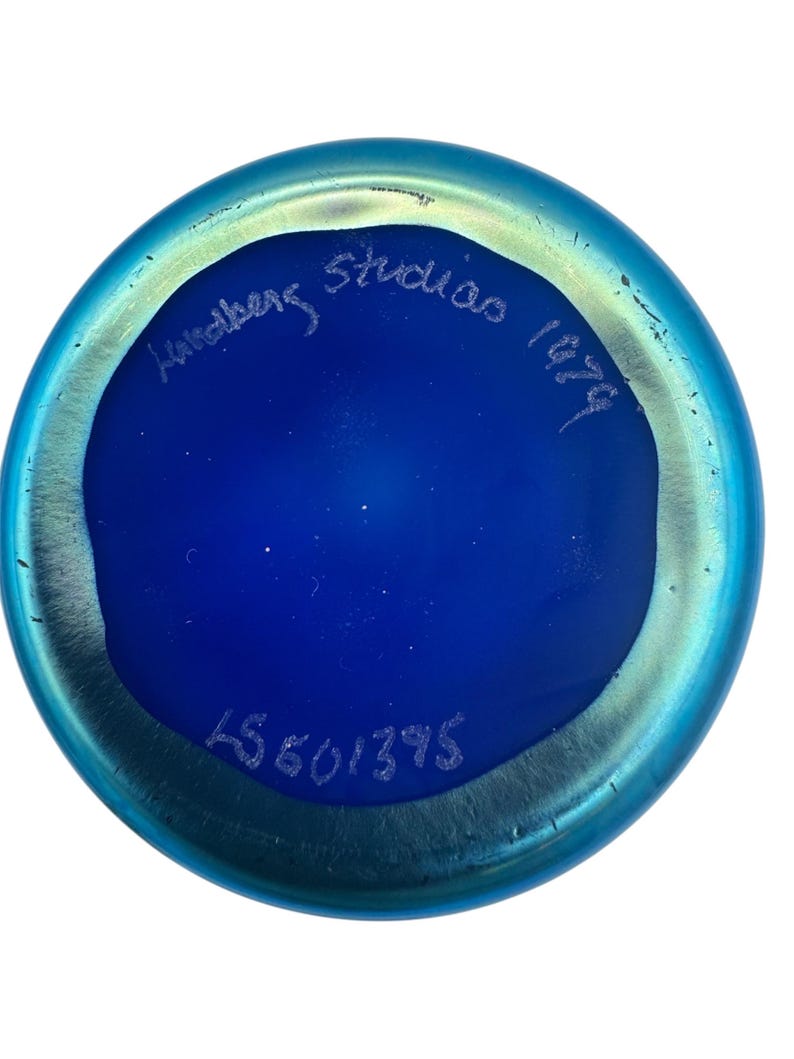 May include: A blue glass vase with an iridescent finish. The bottom of the vase is marked with "Hultberg Studio 1979" and a number "15601395".