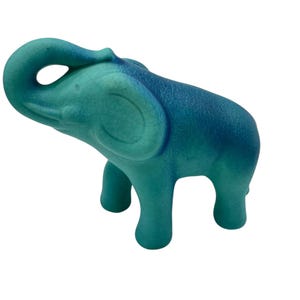 May include: A ceramic elephant figurine in shades of teal and blue. The elephant has a raised trunk and is standing on four legs. The figurine has a textured surface and is a decorative item.