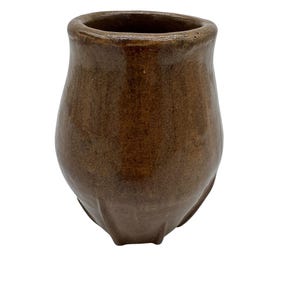 May include: A brown ceramic vase with a rounded body and a slightly flared rim. The vase has a smooth, glossy finish and a dark brown color. The base of the vase has three small feet.