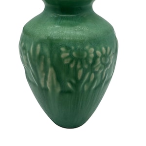 May include: A green ceramic vase with a raised floral design. The vase has a rounded body and a narrow neck.