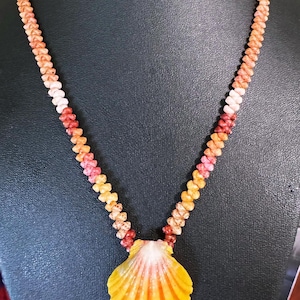 May include: A multi-colored shell lei with a large, yellow, orange, and pink shell pendant.