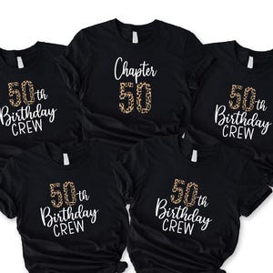 May include: Five black t-shirts with white and leopard print text. The shirts say "50th Birthday Crew" and "Chapter 50". The number 50 has a leopard print design.