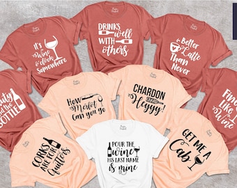 May include: Nine different t-shirts with wine-themed sayings. The shirts are in various colors, including peach, white, and red.