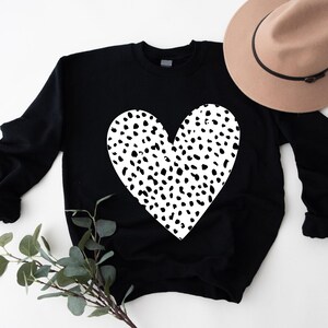 a black sweater with a white heart on it