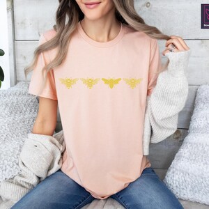 a woman sitting on a bed wearing a pink shirt