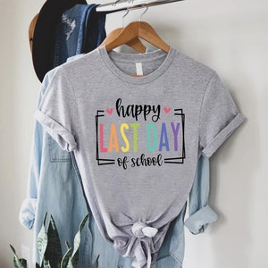 May include: Grey t-shirt with the text "happy last day of school" in a rainbow colour scheme with pink hearts.