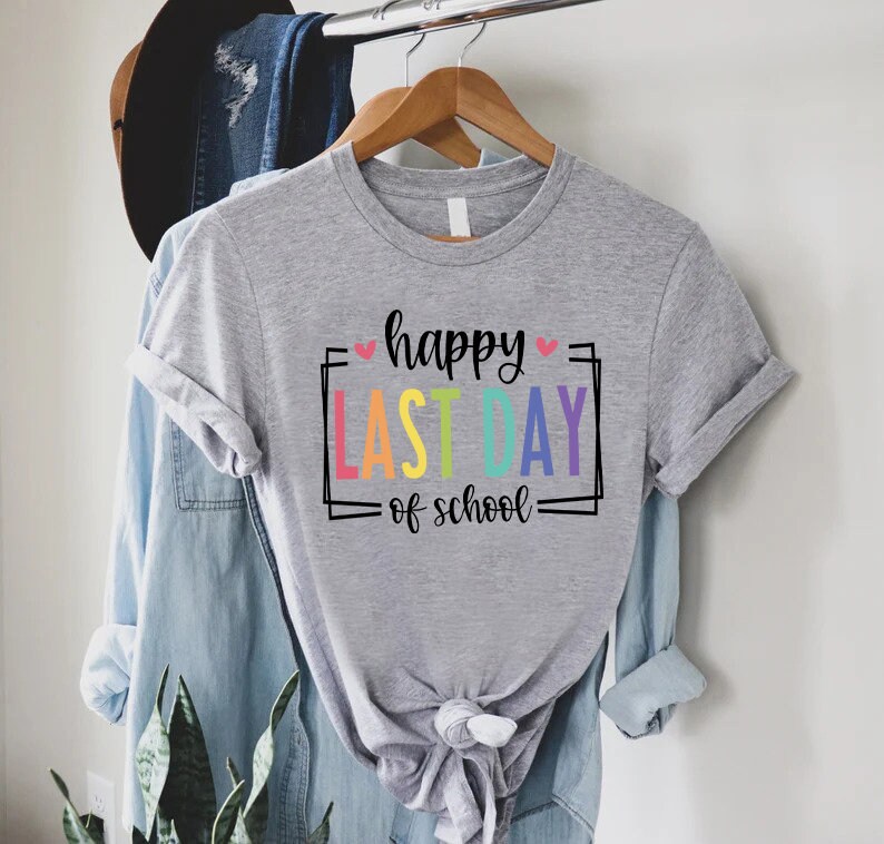 May include: Grey t-shirt with the text "happy last day of school" in a rainbow colour scheme with pink hearts.