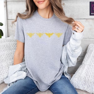 a woman sitting on a bed wearing a grey shirt