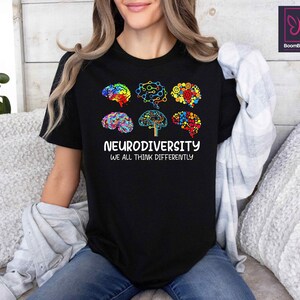 K&ouml;nnte beinhalten: Schwarzes T-Shirt mit einer Grafik aus bunten Hirn-Umrei&szlig;ungen, die einen Baum mit dem Text "Neurodiversity We All Think Differently" bilden.