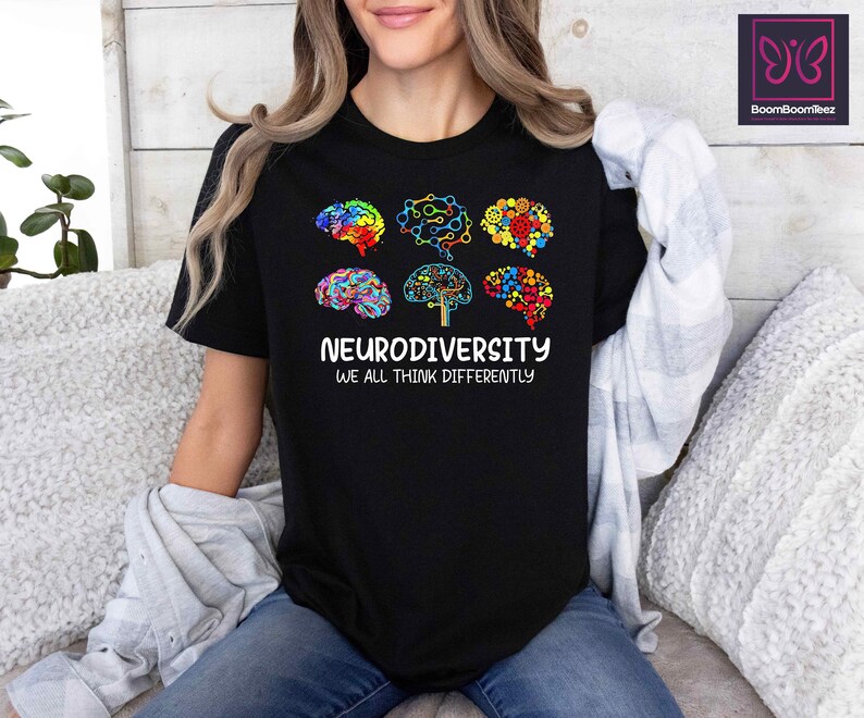 K&ouml;nnte beinhalten: Schwarzes T-Shirt mit einer Grafik aus bunten Hirn-Umrei&szlig;ungen, die einen Baum mit dem Text "Neurodiversity We All Think Differently" bilden.
