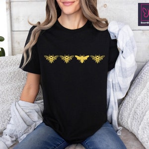 a woman sitting on a couch wearing a black shirt with yellow butterflies on it