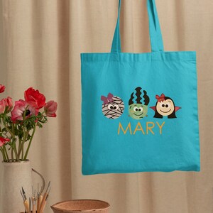 a person holding a blue bag with two monsters on it