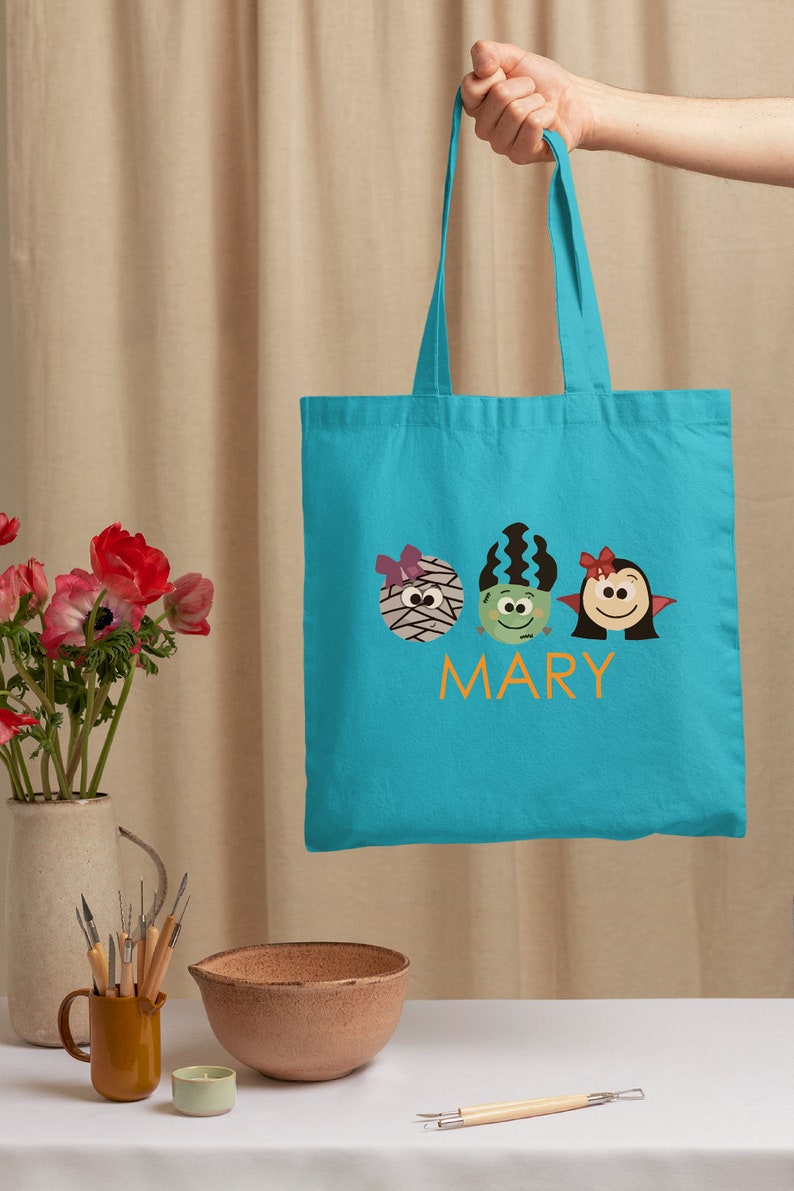 a person holding a blue bag with two monsters on it