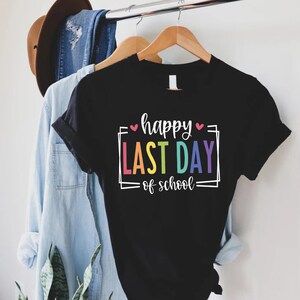 May include: Black t-shirt with the text "happy last day of school" in a rainbow font with pink hearts.