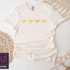 a white t - shirt with a yellow butterfly on it