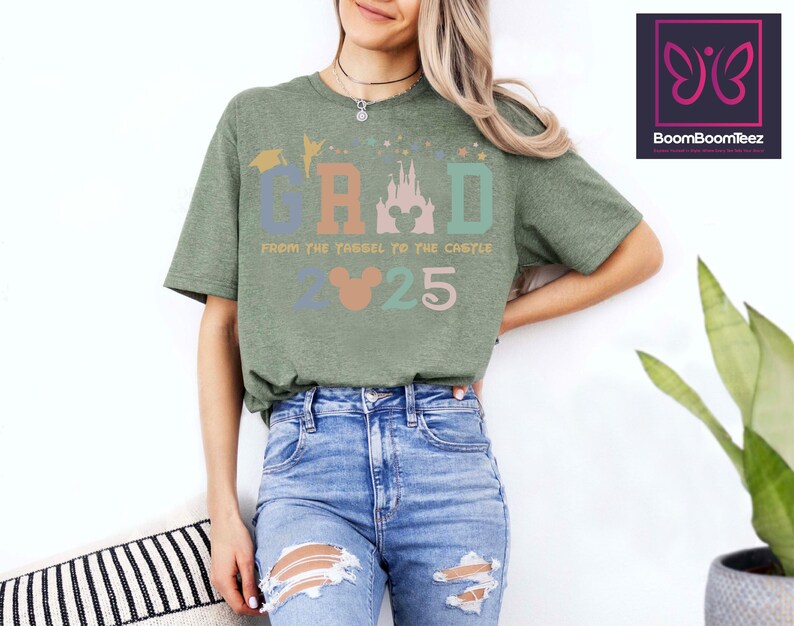 May include: Green short-sleeved t-shirt with a colorful graphic that says "GRAD" with a Mickey Mouse head and castle silhouette. The text below says "From the tassel to the castle 2025".