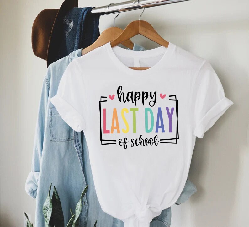 May include: White t-shirt with the text "happy last day of school" in a rainbow colour scheme.