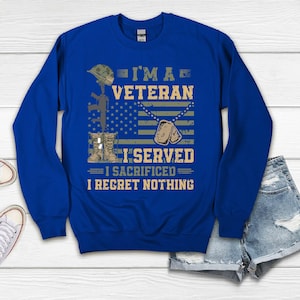 以下が含まれることがあります： ロイヤルブルーのスウェットシャツに、白と黒で「I'm a Veteran I Served I Sacrificed I Regret Nothing」の文字が書かれています。デザインには、迷彩柄の兵士のヘルメット、ライフル、ドッグタグが含まれています。