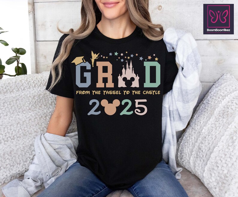 May include: Black t-shirt with a colorful graphic that says "GRAD" with a Mickey Mouse head and castle silhouette. The text below says "From the tassel to the castle 2025".