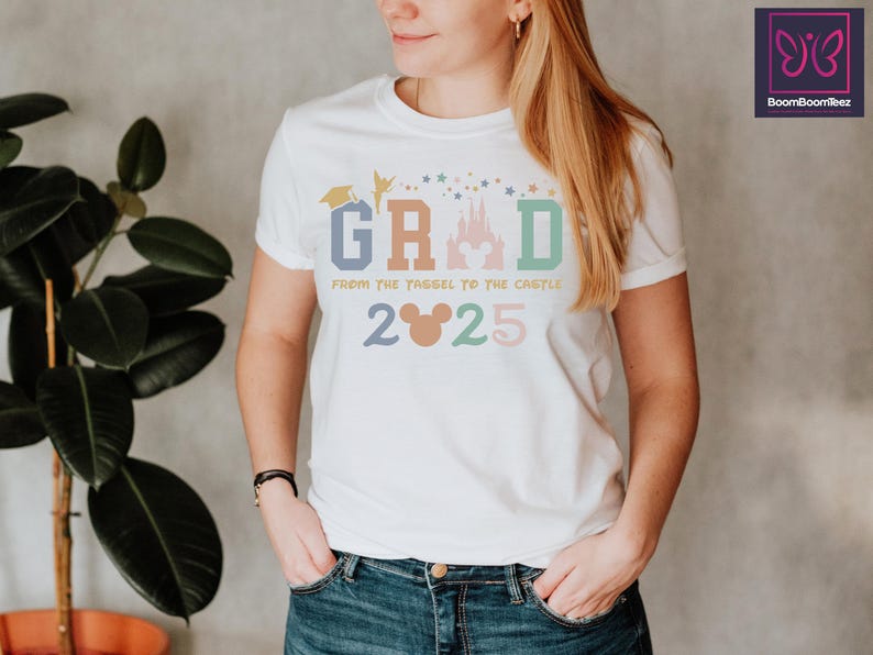 May include: White t-shirt with a colorful graphic that says "GRAD from the YAGEL to the CASTLE 2025". The graphic includes a graduation cap, a fairy, a castle, and Mickey Mouse ears.