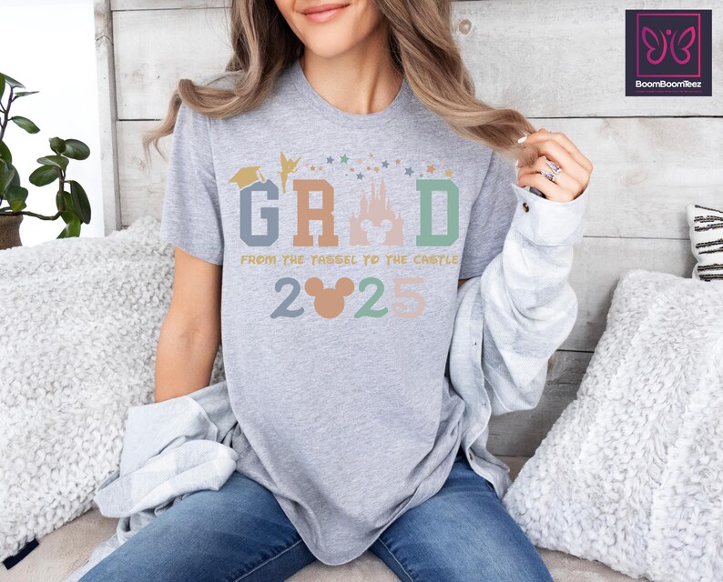 May include: Gray t-shirt with a colorful graphic of a castle, stars, and the text "GRAD from the tassel to the castle 2025" with a Mickey Mouse head.