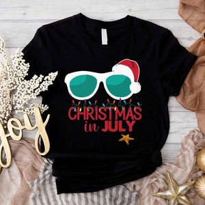 a black t - shirt with the words merry christmas in july on it