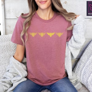 a woman sitting on a bed with a bat t - shirt on
