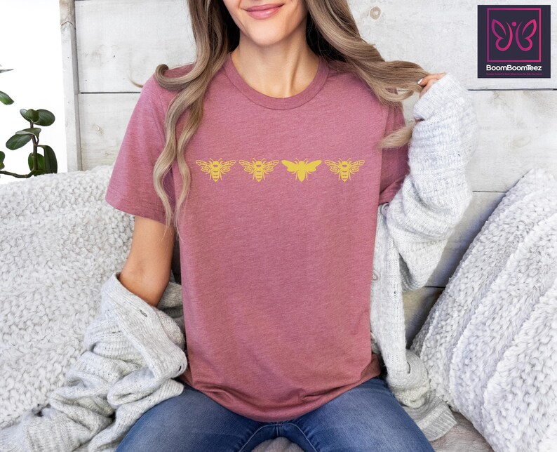 a woman sitting on a bed with a bat t - shirt on
