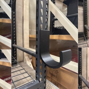 Puede incluir: Una colección de ganchos y soportes metálicos negros y amarillos diseñados para fijarse a una estantería metálica. Los ganchos tienen varias formas, incluyendo un gancho en J, un soporte en forma de copa y un soporte tipo estante.