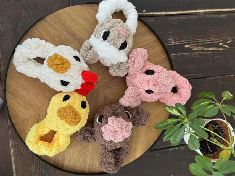 May include: Five plush animal headbands in different colours and animal designs. The headbands are made of soft, fuzzy material and feature embroidered eyes and noses. The animals include a chicken, a pig, a cow, a bunny, and a duck.