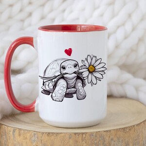 Puede incluir: Taza de cer&aacute;mica blanca con borde y asa rojos. La taza presenta una ilustraci&oacute;n en blanco y negro de una tortuga sosteniendo una margarita con un coraz&oacute;n rojo encima.