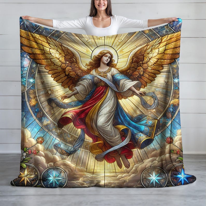 May include: A large, rectangular blanket featuring a stained-glass style angel design. The angel has golden wings, flowing robes in white, red, and blue, and is surrounded by a halo and celestial elements. The blanket is held up by a person.