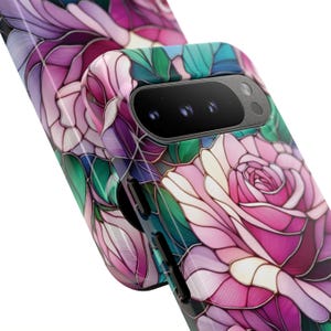 May include: A phone case featuring a stained-glass floral design with pink, purple, and green hues. The case has a glossy finish and a camera cutout. The design resembles a rose with intricate details and a mosaic effect.