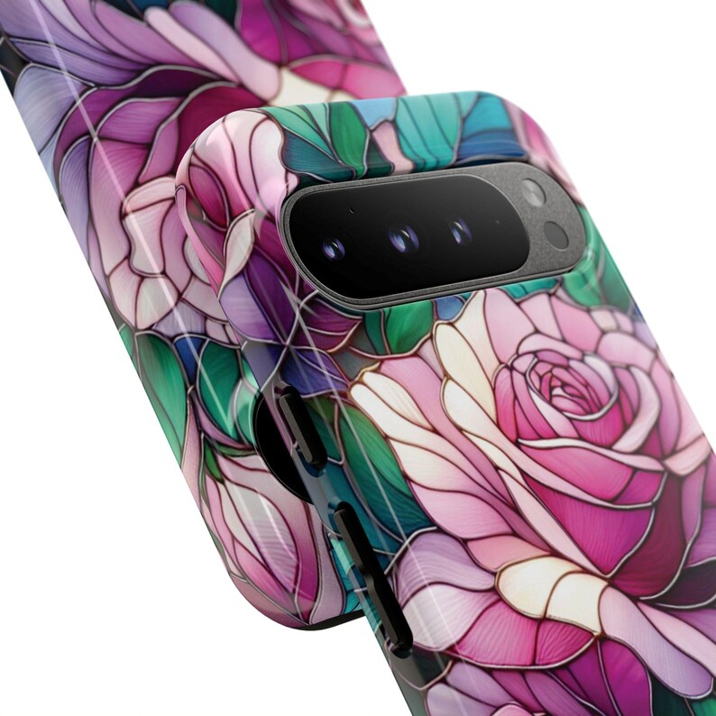 May include: A phone case featuring a stained-glass floral design with pink, purple, and green hues. The case has a glossy finish and a camera cutout. The design resembles a rose with intricate details and a mosaic effect.
