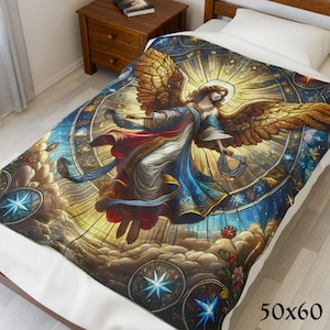 May include: A 50x60 inch blanket featuring a detailed illustration of an angel with golden wings, set against a stained-glass style background. The design includes a halo, clouds, and celestial elements in shades of blue, gold, and red.