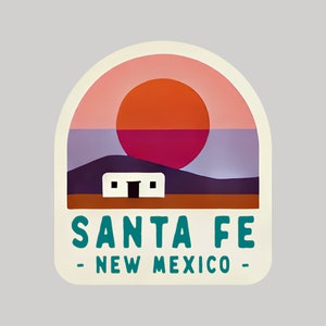May include: A sticker featuring a landscape design with a sunset and a white building. The text "SANTA FE - NEW MEXICO" is in teal. The background has shades of pink, orange, purple, and brown.