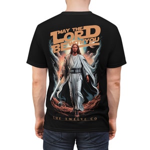 May include: Black t-shirt featuring a graphic of a figure in white robes holding a lightsaber, with the text "MAY THE LORD BE WITH YOU" in orange and white. The Twelve Co logo is at the bottom.