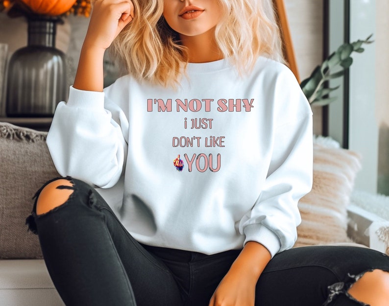 May include: White sweatshirt with the text 'I'M NOT SHY i JUST DON'T LIKE YOU' in pink lettering.