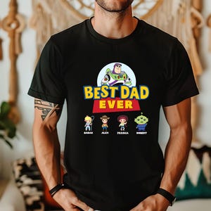 May include: Black t-shirt with the text "BEST DAD EVER" in yellow and blue, featuring cartoon characters. Below the text are four cartoon characters with names: Sarah, Alex, Jessica, and Robert.