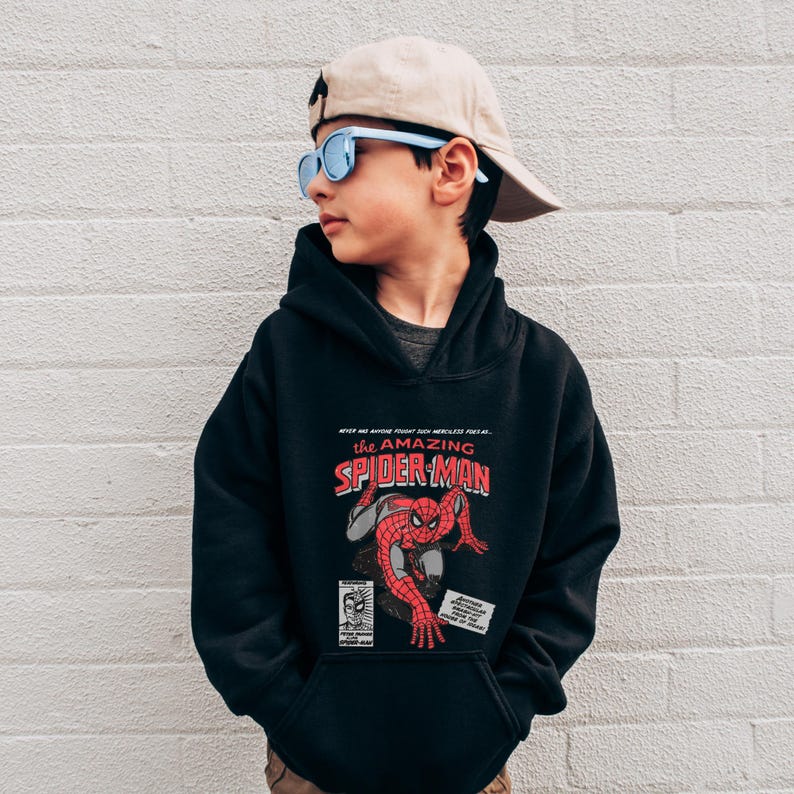 May include: Black hooded sweatshirt with a graphic print of Spider-Man. The text "the amazing SPIDER-MAN" is printed in red on the front of the sweatshirt.