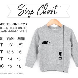 May include: Size chart for a toddler fleece unisex crewneck sweatshirt. The chart shows sizes 2T, 3T, 4T, and 5/6 with corresponding width and length measurements in inches.