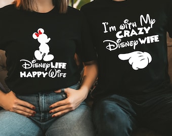 Könnte beinhalten: Schwarze T-Shirts mit weißen Grafiken. Ein Shirt zeigt eine Mickey Mouse Silhouette und den Text "Disney Life Happy Wife". Das andere Shirt sagt "I'm with My Crazy Disney Wife" mit einer Hand-Grafik, die zeigt. Ein lustiges passendes Set für Paare.