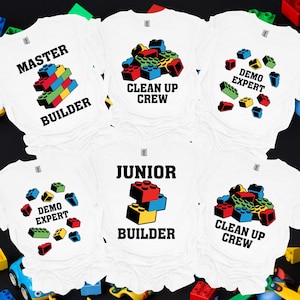 May include: Five white t-shirts with different designs featuring colorful toy building blocks and text. The shirts say "Master Builder", "Clean Up Crew", "Demo Expert", "Junior Builder", and "Clean Up Crew".