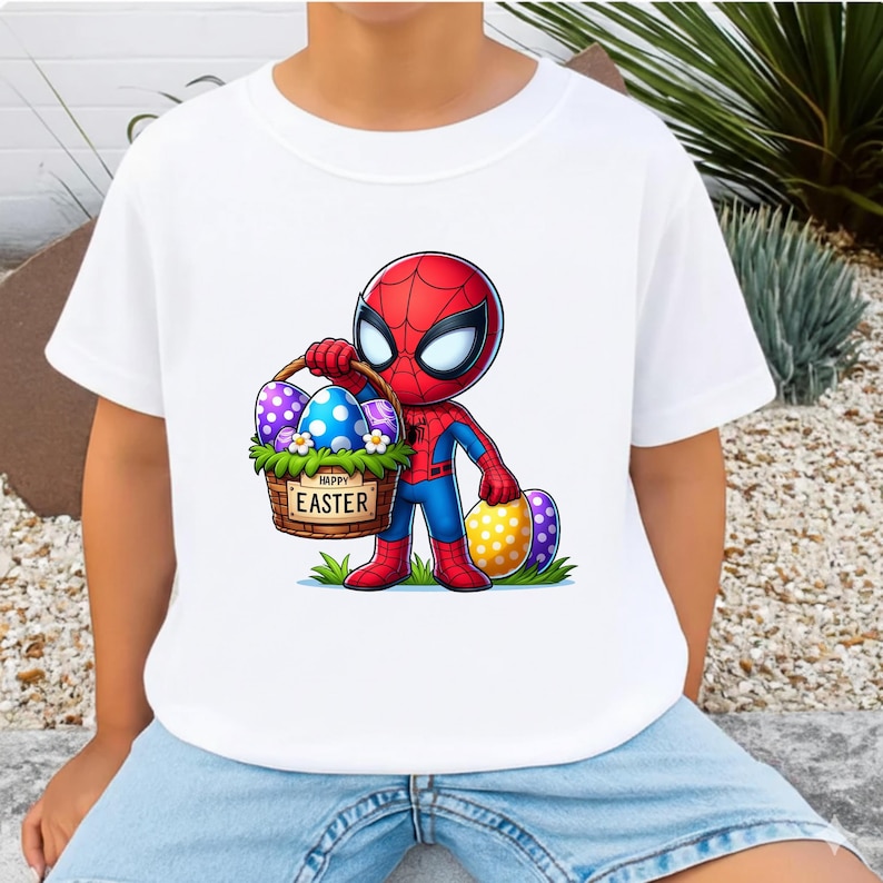 Puede incluir: Camiseta blanca con un personaje de dibujos animados de Spider-Man sosteniendo una cesta de Pascua. La cesta tiene el texto "Happy Easter". Los huevos est&aacute;n decorados con varios patrones y colores. El personaje lleva un traje rojo y azul.