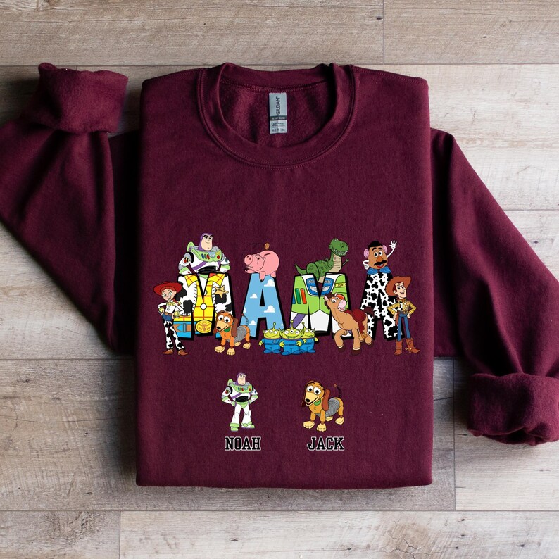 Może przedstawiać: Bordowa bluza z grafiką postaci z Toy Story, kt&oacute;re tworzą napis "MAMA" z nazwami "Noah" i "Jack" poniżej.