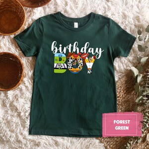 K&ouml;nnte beinhalten: Ein dunkelgr&uuml;nes T-Shirt mit den Worten "birthday boy" in wei&szlig;en Buchstaben. Die Buchstaben sind mit Bildern von Figuren aus dem Toy Story-Film-Franchise verziert.