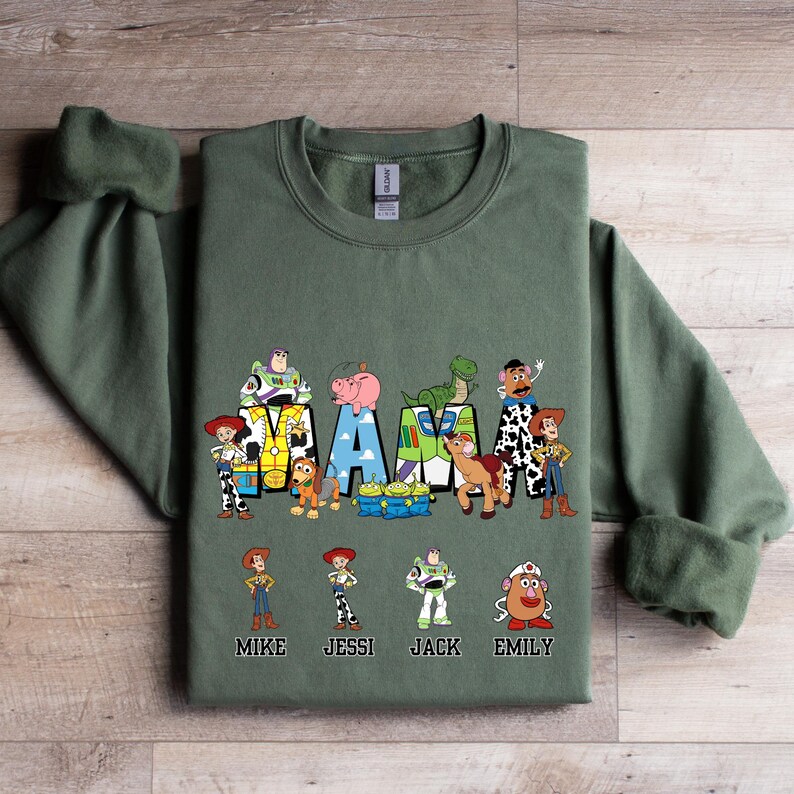 Może przedstawiać: Zielony sweter z grafiką postaci z Toy Story, kt&oacute;re tworzą napis "MAMA" z nazwami Mike, Jessie, Jack i Emily pod spodem.