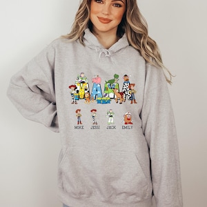 Może przedstawiać: Szara bluza z kapturem z grafiką postaci z Toy Story, kt&oacute;re tworzą napis "MAMA" z nazwami Mike, Jessi, Jack i Emily poniżej.