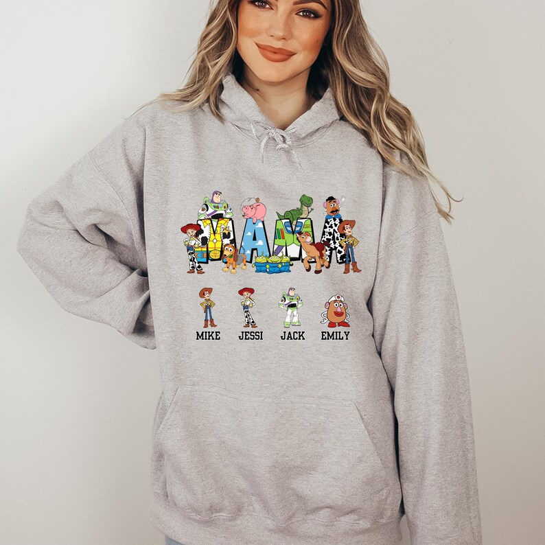 Może przedstawiać: Szara bluza z kapturem z grafiką postaci z Toy Story, kt&oacute;re tworzą napis "MAMA" z nazwami Mike, Jessi, Jack i Emily poniżej.