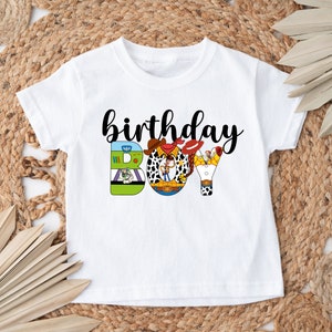 K&ouml;nnte beinhalten: Wei&szlig;es T-Shirt mit einer schwarz-wei&szlig;en Grafik von Toy Story-Charakteren, die "birthday boy" buchstabieren.